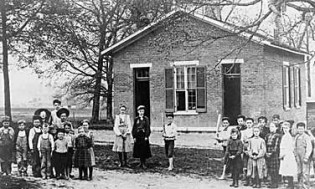 kids in front of one room schoolhouse
